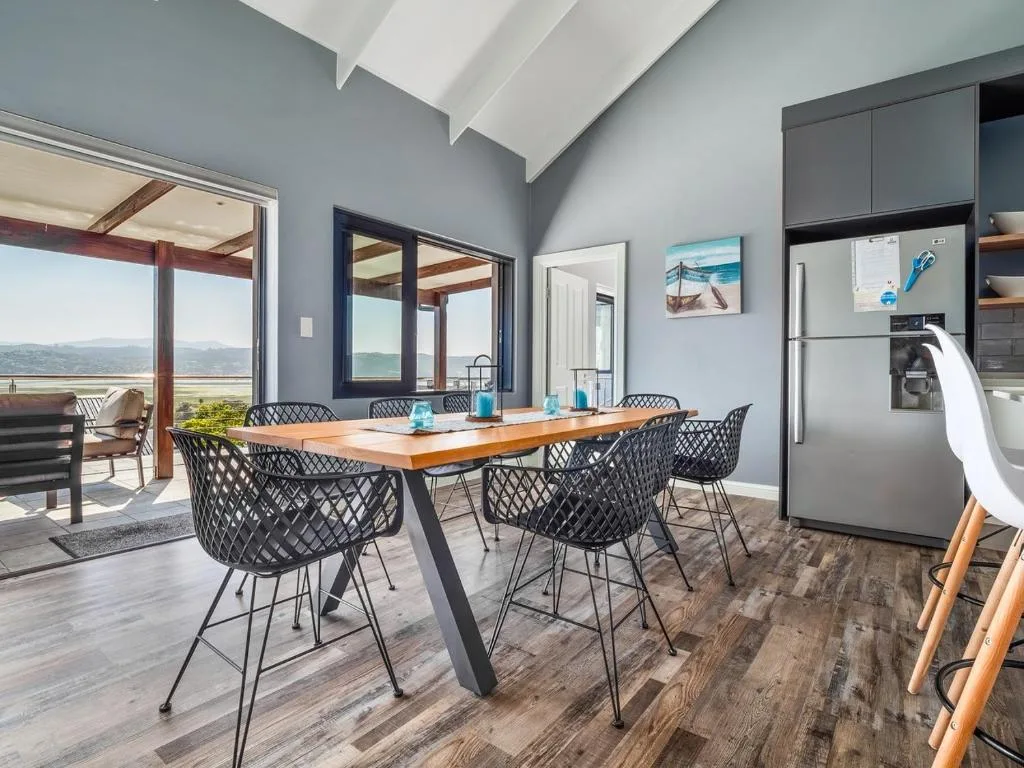 Modern dining area with wooden table, black chairs, and mountain views