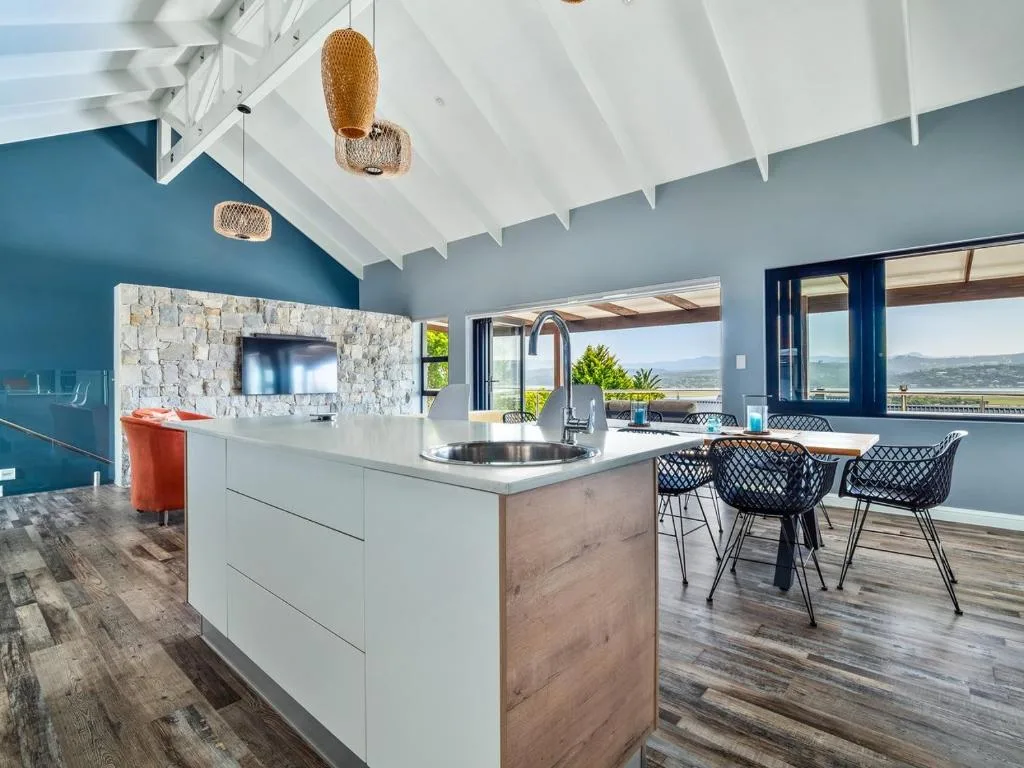 Modern open-plan kitchen with island, stone fireplace, and valley views