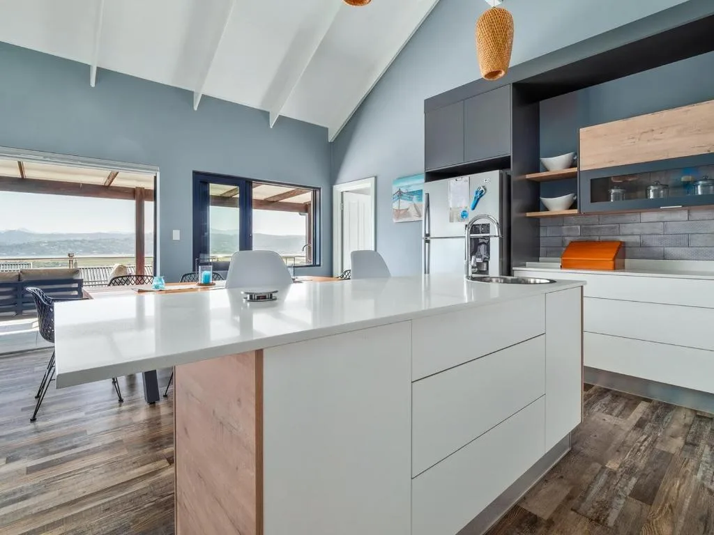 Modern kitchen with white cabinetry, island counter, and scenic garden route views