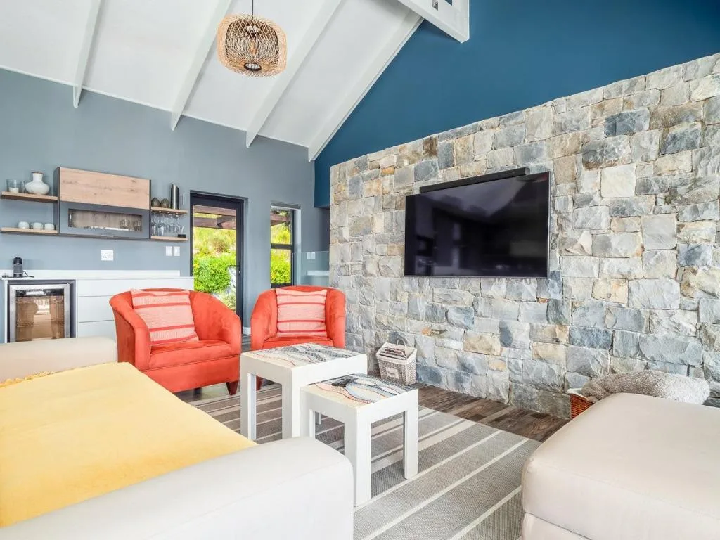 Modern lounge with red armchairs, stone fireplace, and wall-mounted television