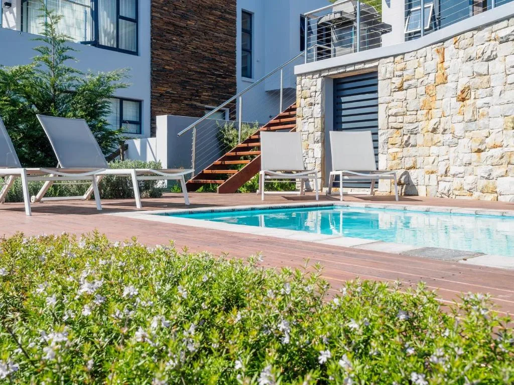 Swimming pool with loungers and stone building on deck area