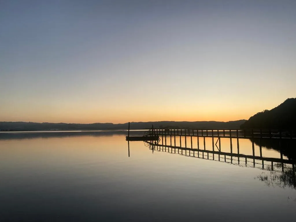 Serene lagoon sunrise with wooden dock reflecting golden light