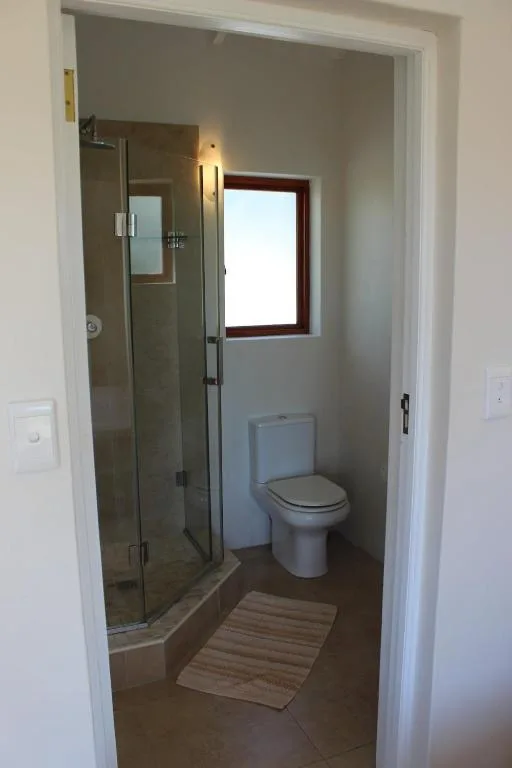 Modern bathroom with glass shower enclosure, toilet, and window