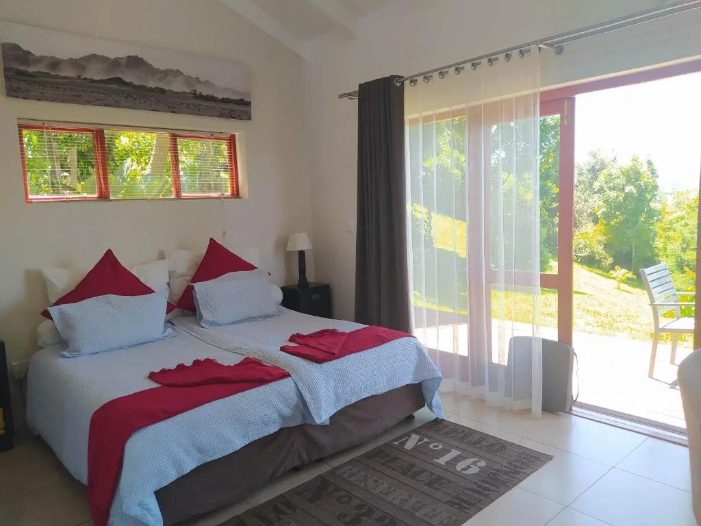 Bright bedroom with twin beds, red accents, and sliding doors to garden views