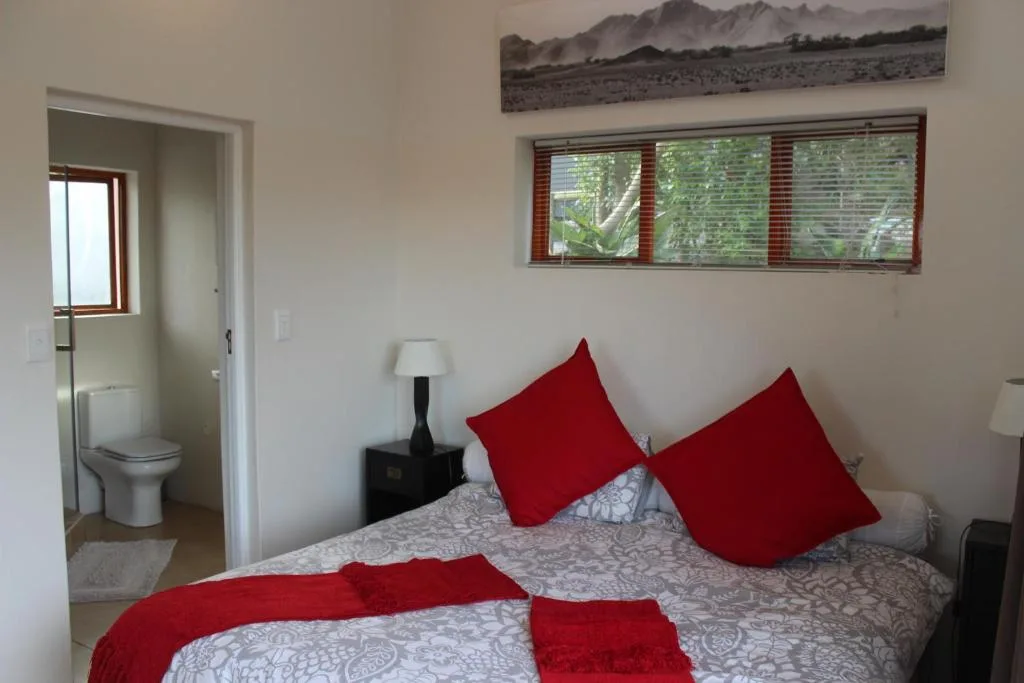 Bright bedroom with red accents, en-suite bathroom visible through open door