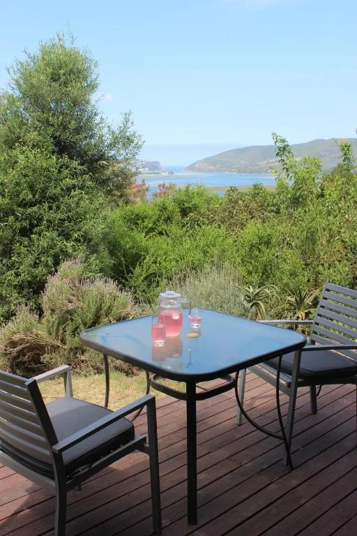 Outdoor deck with table, chairs, and lagoon view beyond