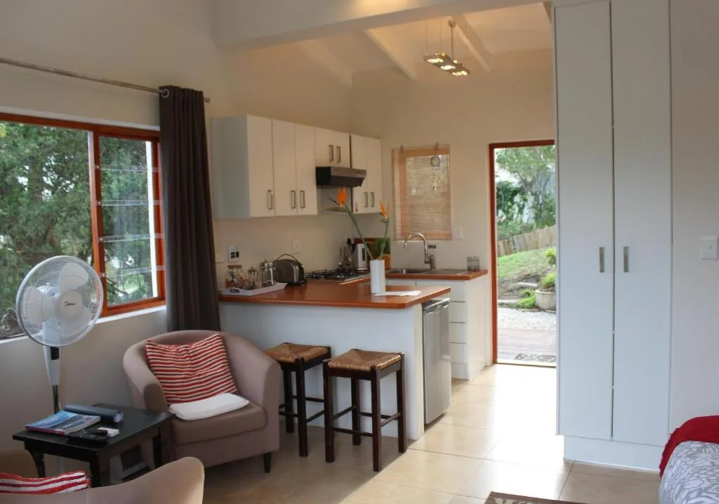 Open-plan kitchen with white cabinetry, wooden countertop, and garden views