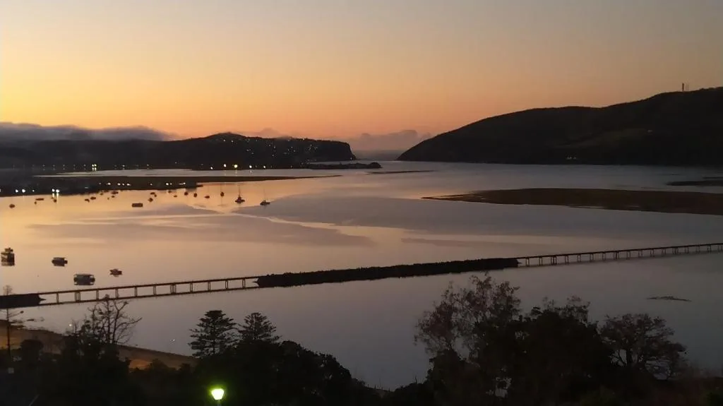 Sunset over Knysna Heads lagoon with moored boats and mountains
