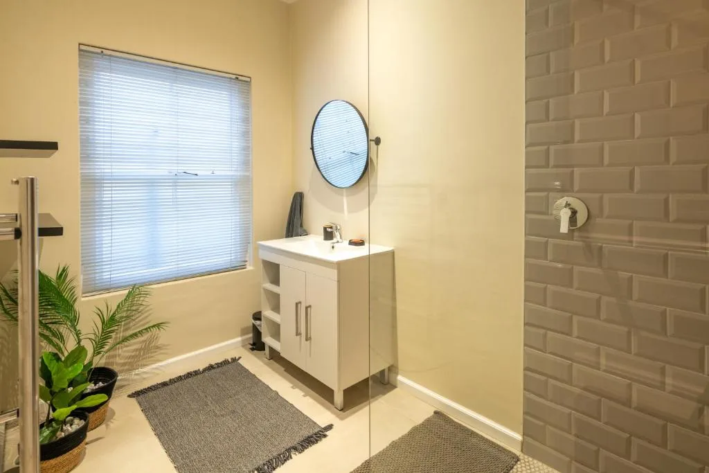Modern bathroom with white vanity, round mirror, brick feature wall