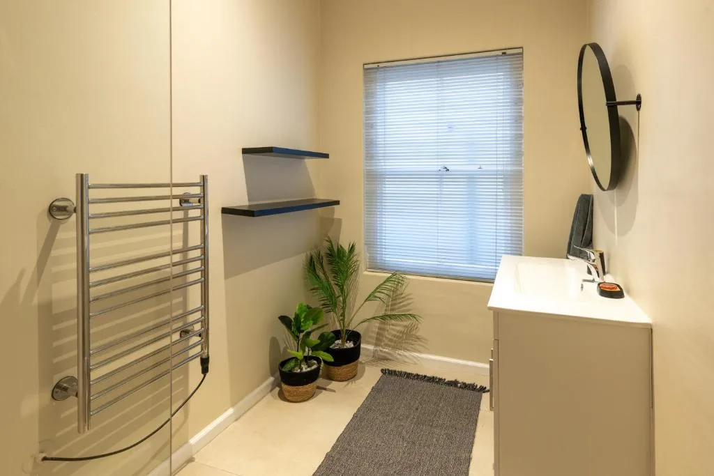 Modern bathroom with heated towel rack, vanity sink, and window blinds
