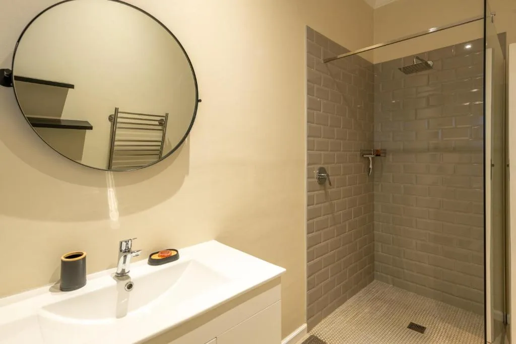 Modern bathroom with vanity sink, round mirror, and spacious walk-in shower