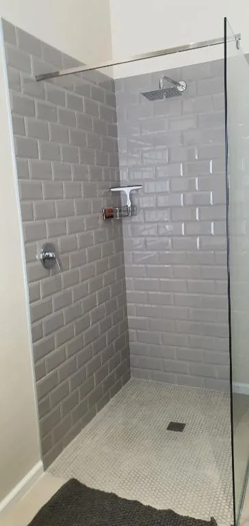Modern shower enclosure with gray subway tiles and rainfall showerhead
