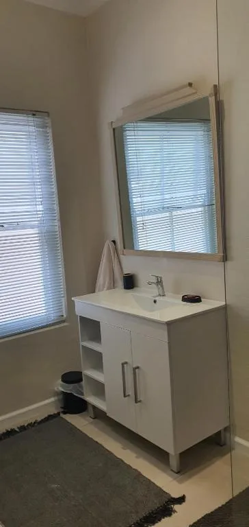Modern bathroom vanity with white cabinet, sink, and mirror above
