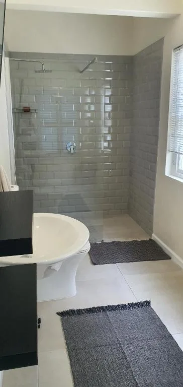 Modern bathroom with white toilet, walk-in shower and grey tile surround
