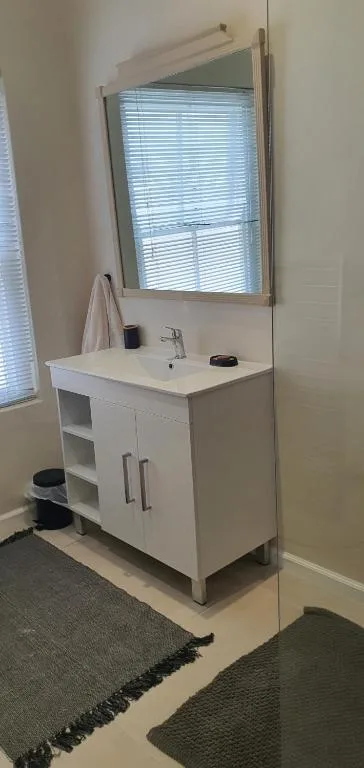 Modern white bathroom vanity with mirror and window blinds
