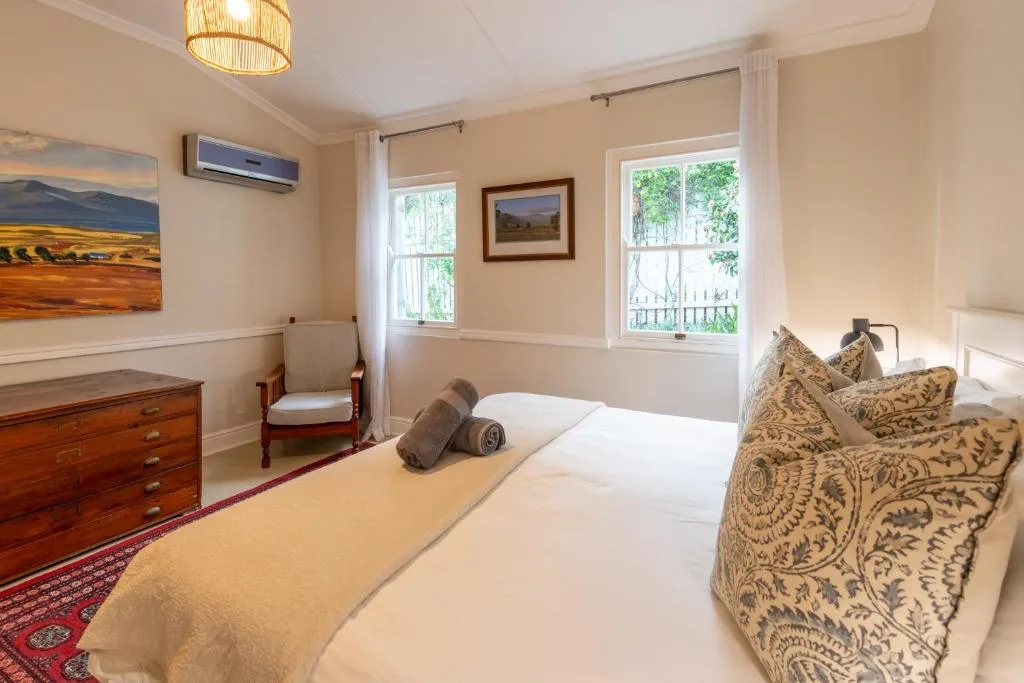 Bright bedroom with queen bed, decorative pillows, wooden dresser, and garden views