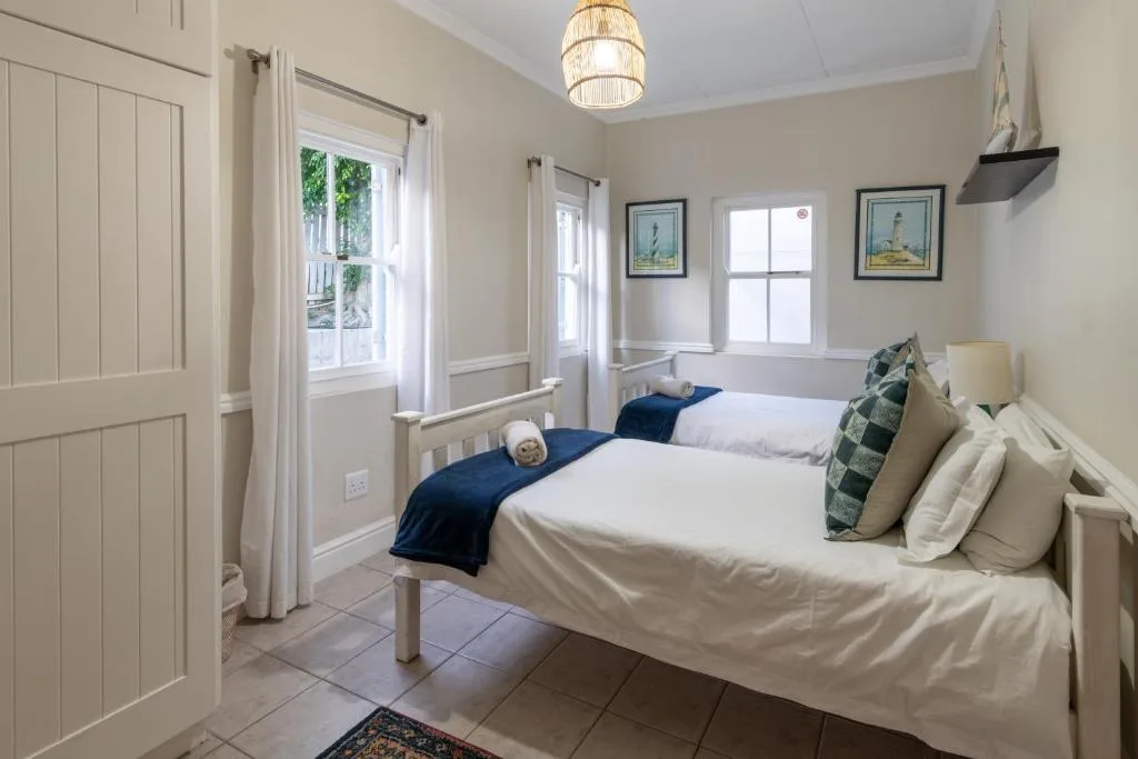 Bright twin bedroom with white linens, navy accents, and garden views