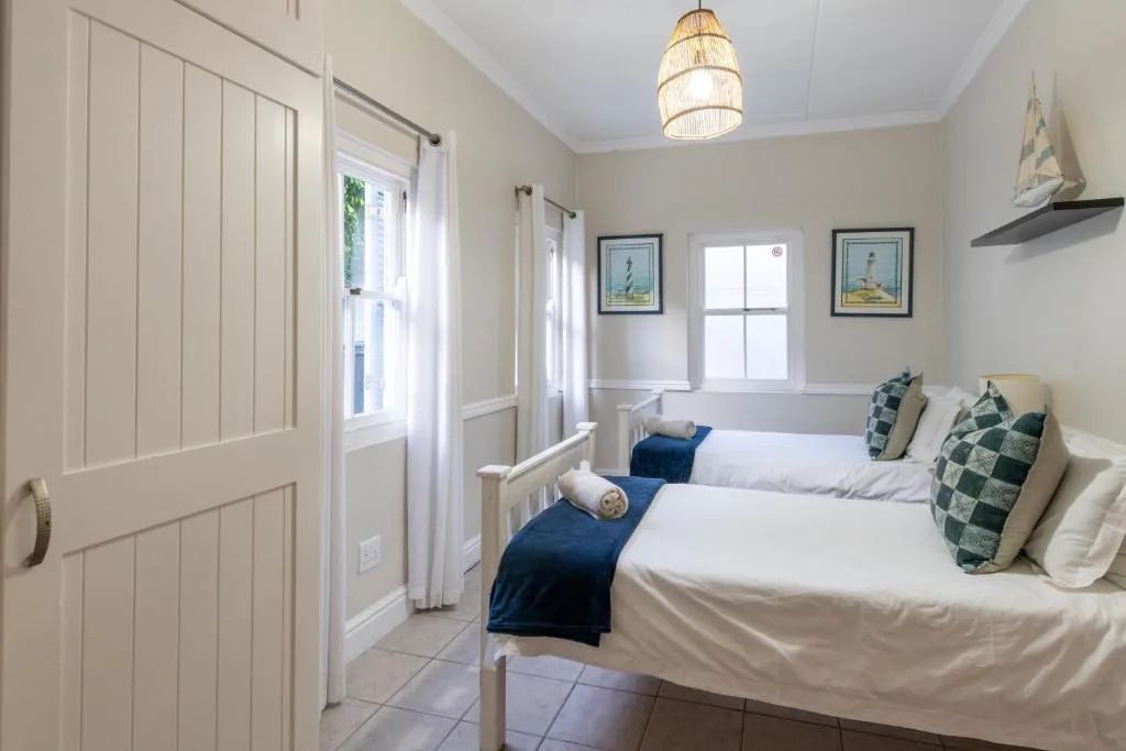 Bright bedroom with two beds, nautical decor, and natural light from windows