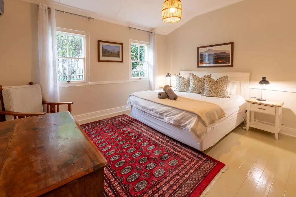 Spacious bedroom with queen bed, patterned throw pillows, and garden views
