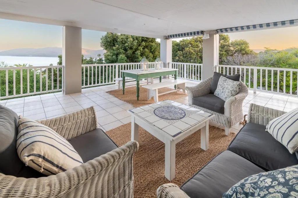 Spacious covered deck with wicker seating, table, and lagoon views
