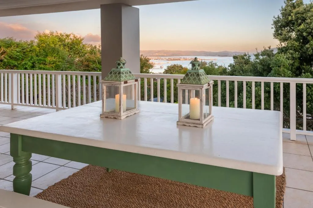 Waterfront deck with table, lanterns, and lagoon views at sunset