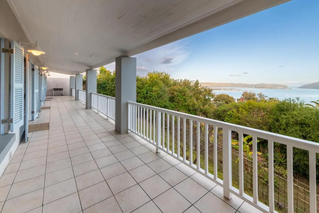 Spacious covered deck with white railings overlooking Knysna lagoon and mountains