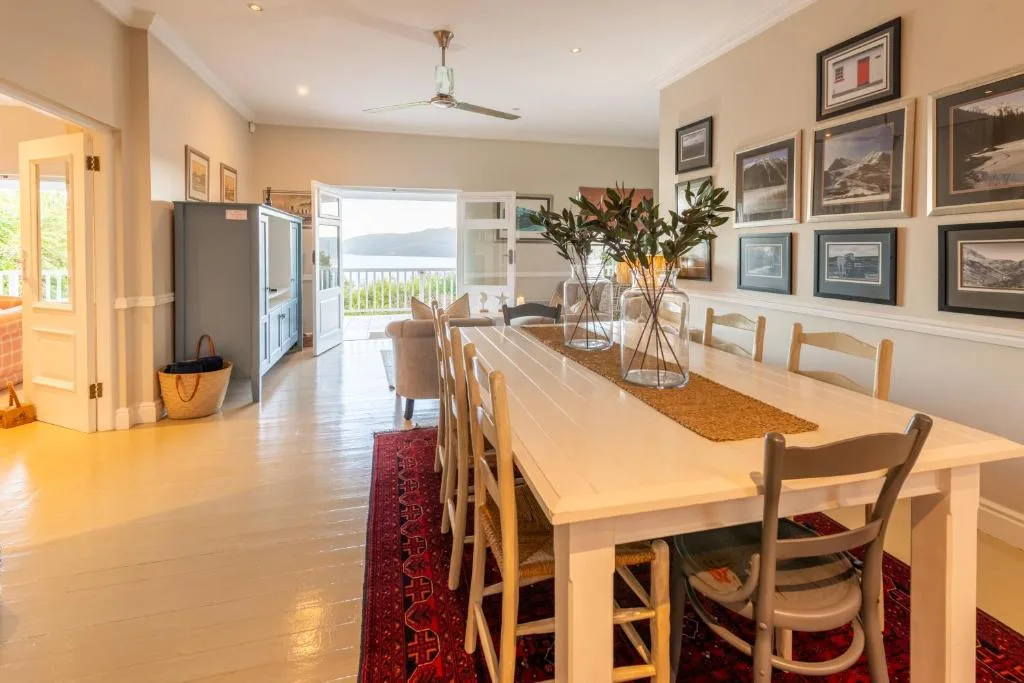 Spacious dining area with wooden table, chairs, and water views beyond
