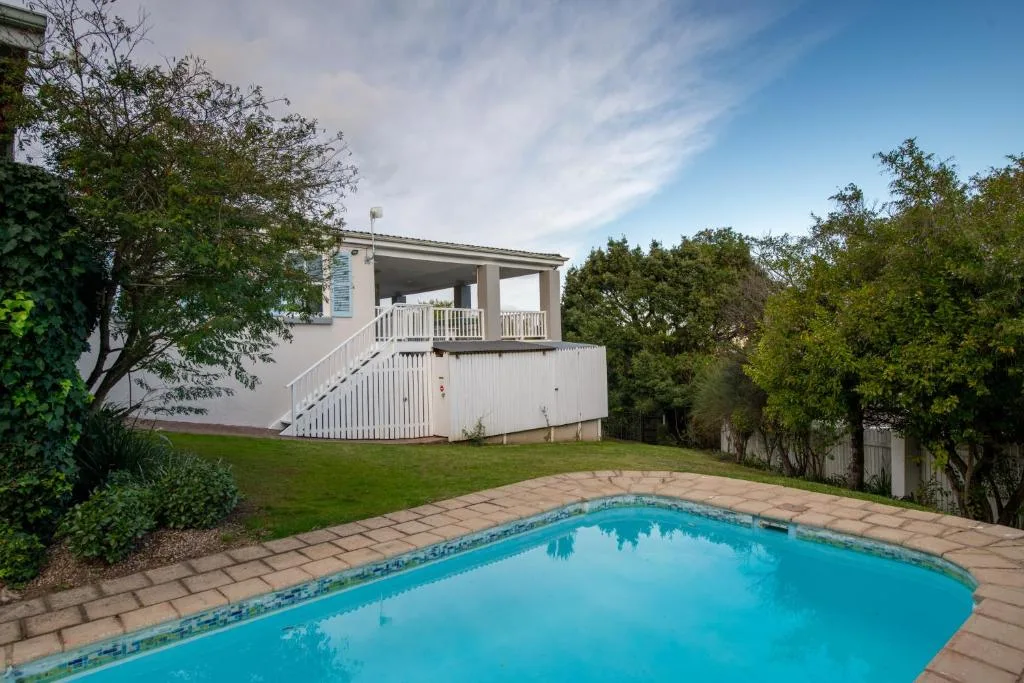 Bright blue swimming pool in front of modern house with gardens