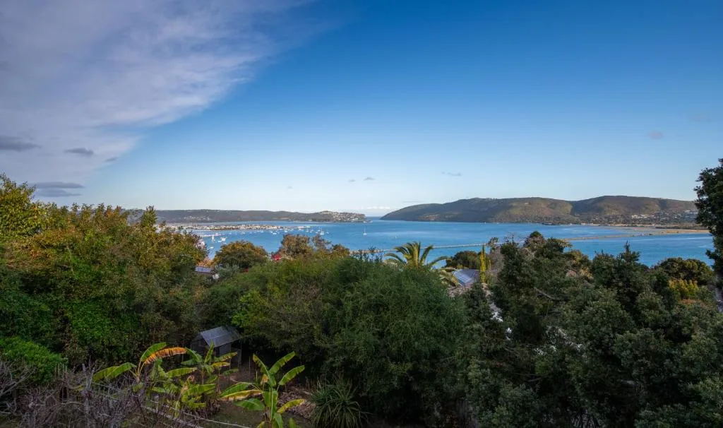 Blue lagoon with moored boats and tree-covered hills beyond