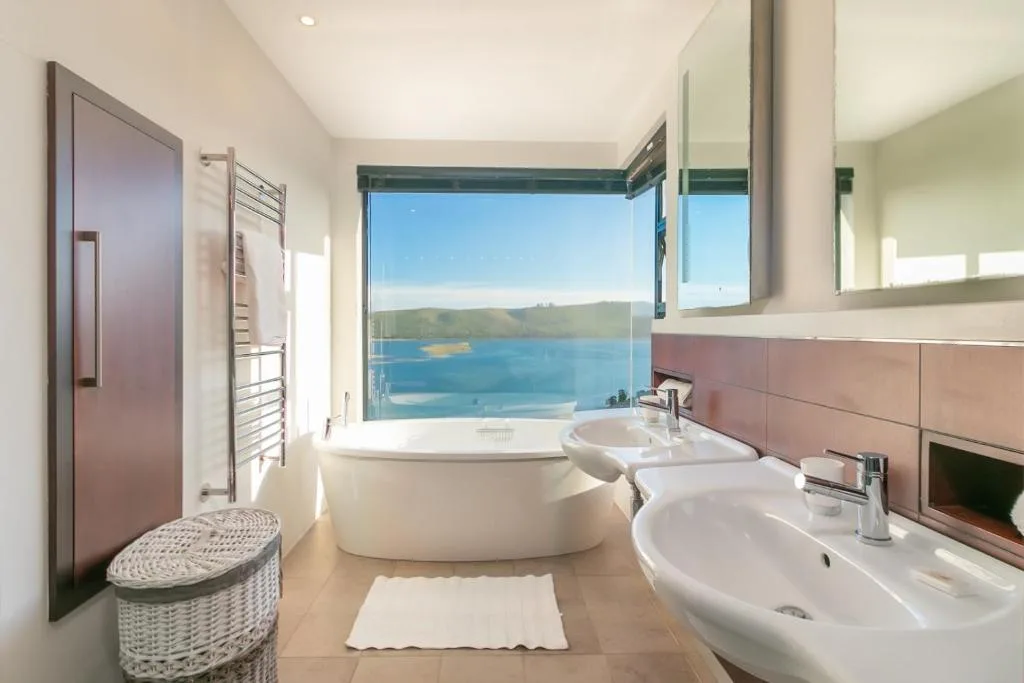Luxurious bathroom with freestanding tub overlooking scenic lagoon and mountains