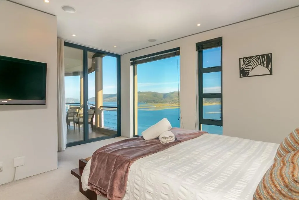 Bedroom with bed overlooking lagoon and mountain views through large glass doors