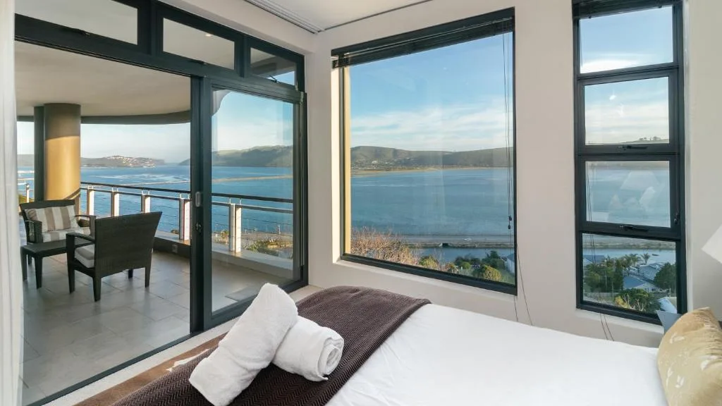 Bedroom with water view through large windows overlooking lagoon
