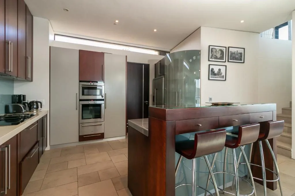 Modern kitchen with dark cabinetry, stainless steel appliances, island counter with bar seating