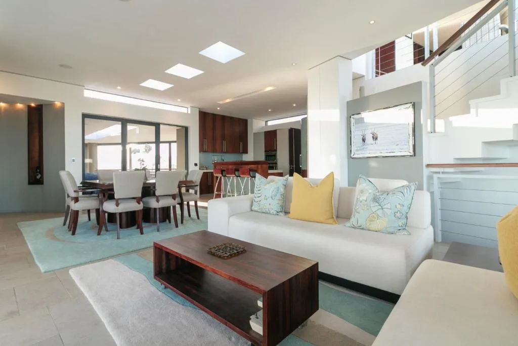 Modern lounge with white sofa, wooden coffee table, and open-plan kitchen beyond