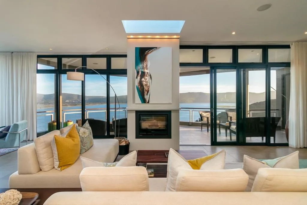 Spacious living room with cream sofas, fireplace, and expansive lagoon views