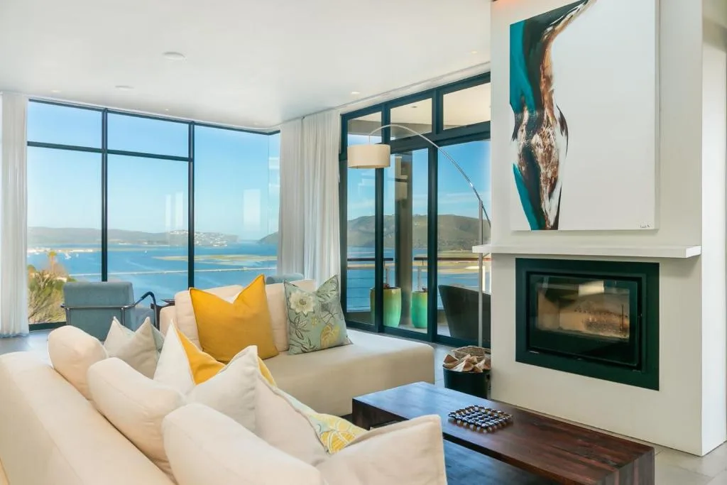 Modern lounge with cream sofa, fireplace, and expansive ocean views