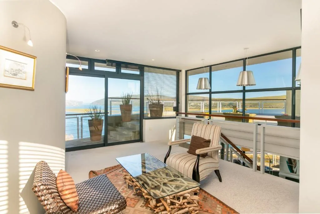 Modern lounge with striped armchair, panoramic lagoon views through floor-to-ceiling windows