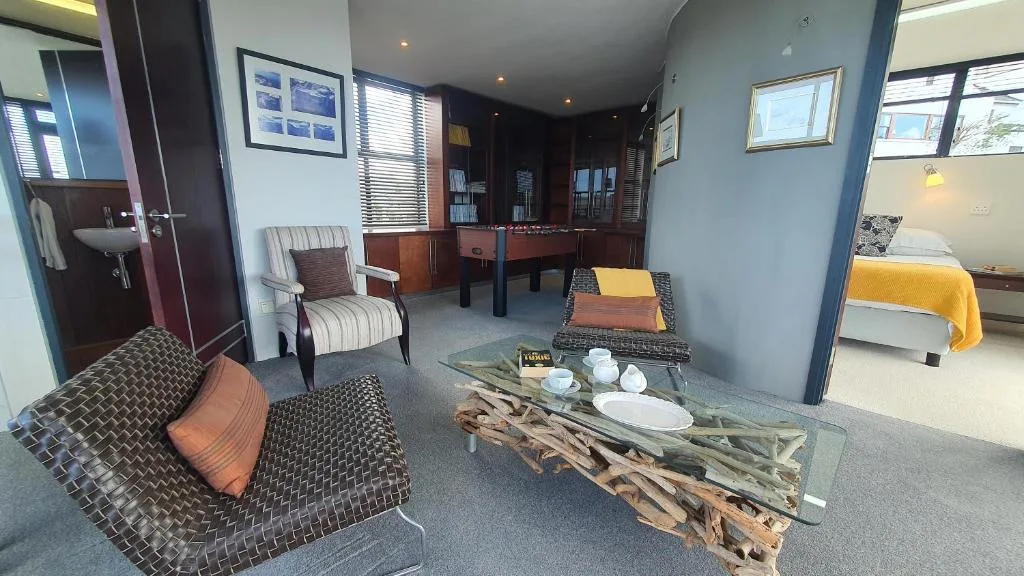 Modern lounge area with striped armchair, driftwood coffee table, and bedroom visible