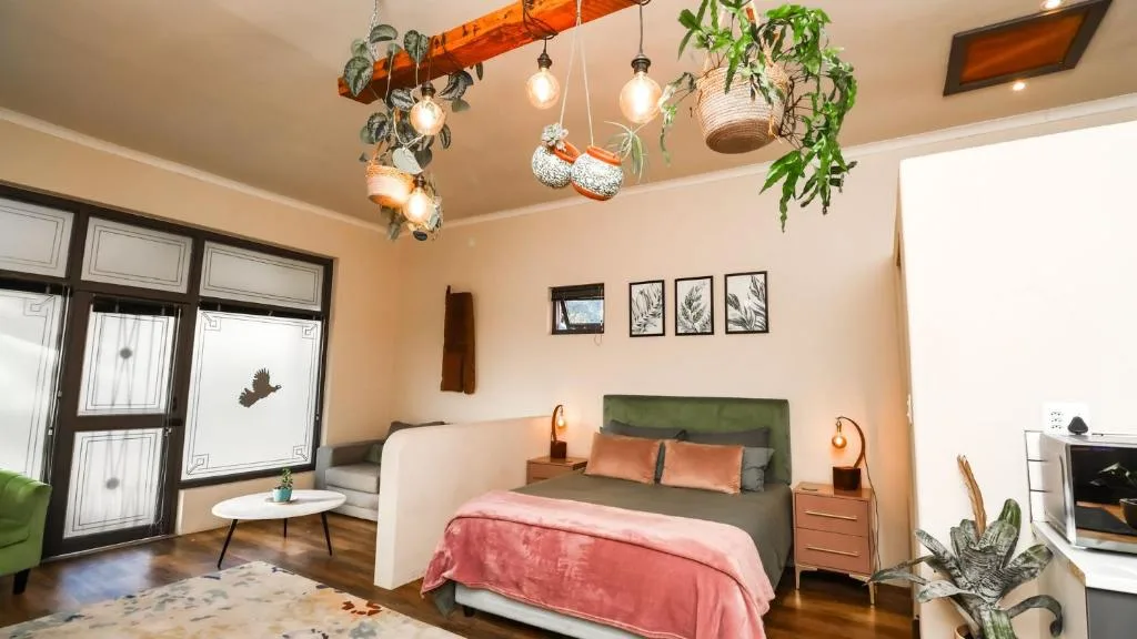 Stylish bedroom with green headboard, pink bedding, and decorative hanging plants overhead