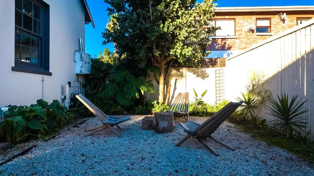 Shaded courtyard with loungers, tree stump seating, and lush tropical plants
