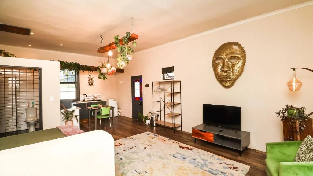 Open-plan lounge with TV, sofa, and contemporary decor featuring gold mask artwork