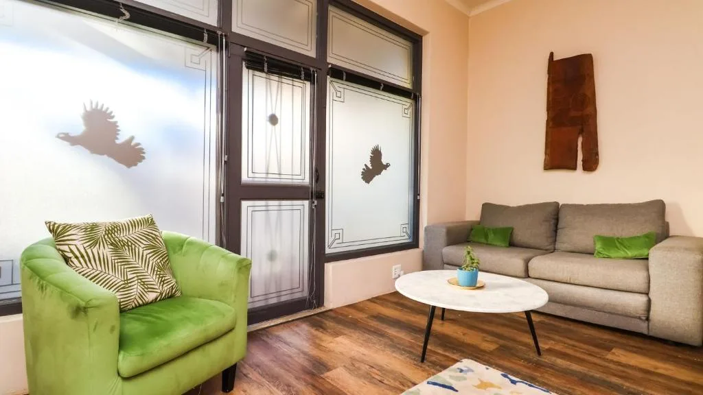 Bright lounge with green armchair, beige sofa, and white coffee table