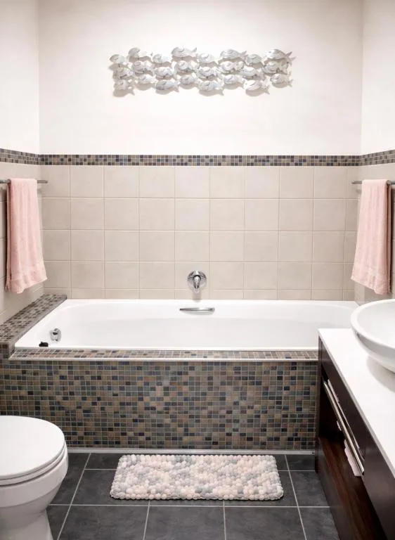 Modern bathroom with soaking tub, decorative wall art, and mosaic tile details