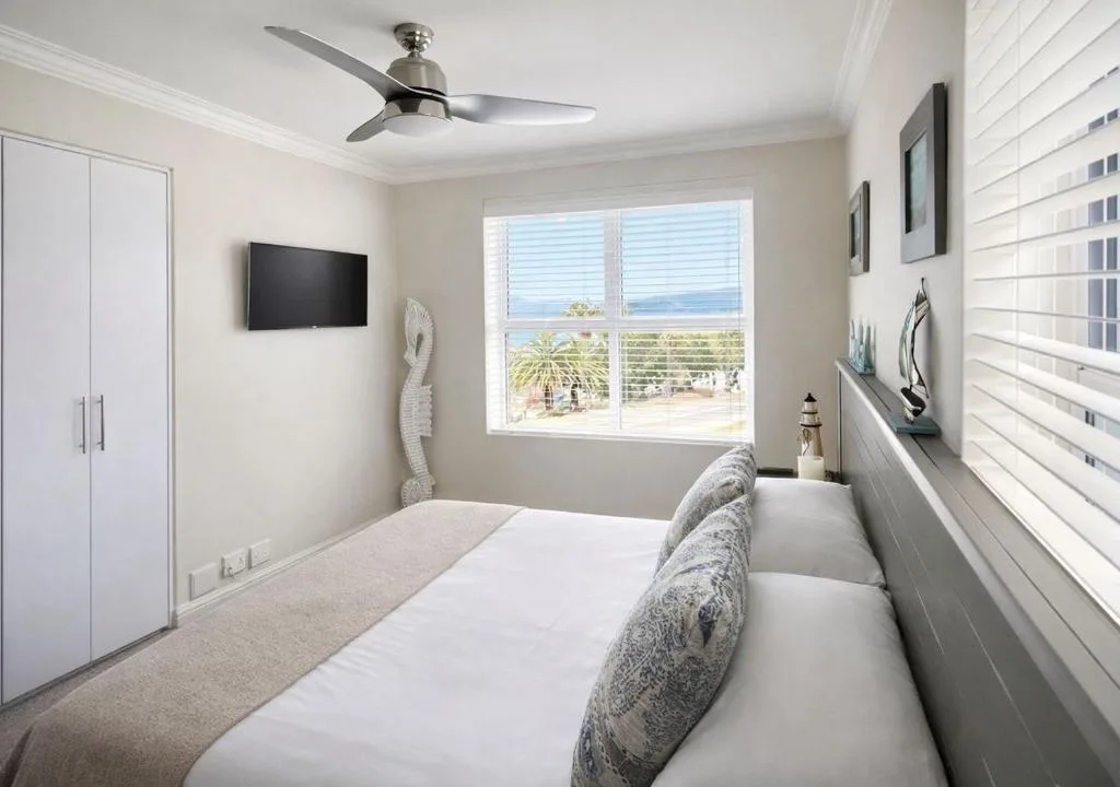 Bright bedroom with ocean view through large windows and modern amenities