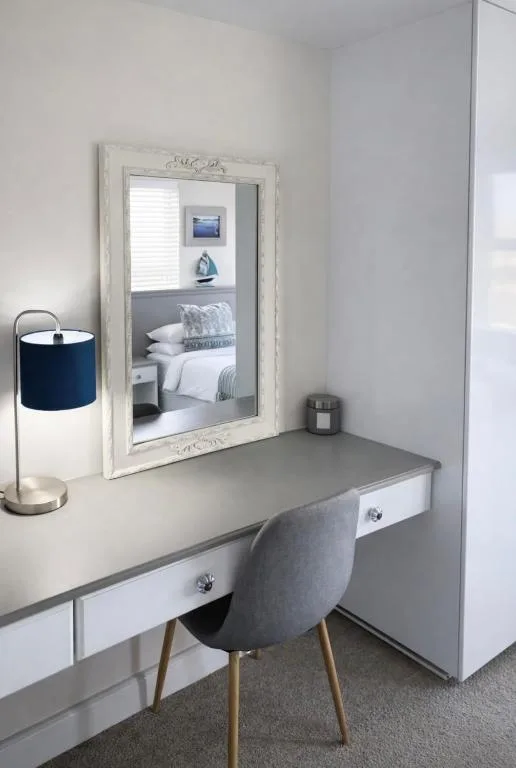 Modern desk with mirror, chair, and blue table lamp in bedroom
