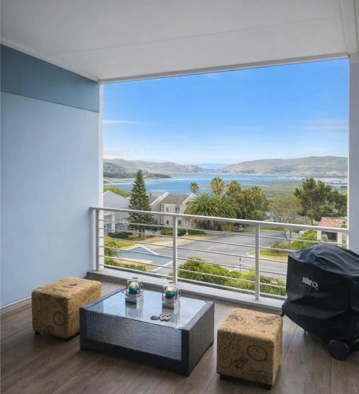 Scenic lagoon and mountain views from modern balcony with seating