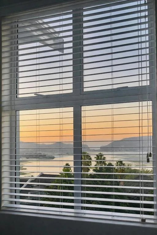 Sunset lagoon view through shuttered windows with palm trees visible