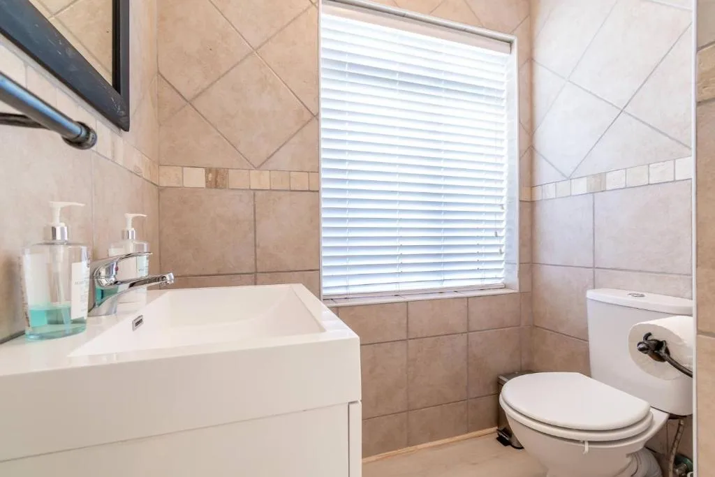 Clean bathroom with vanity sink, toilet, and window with shutters