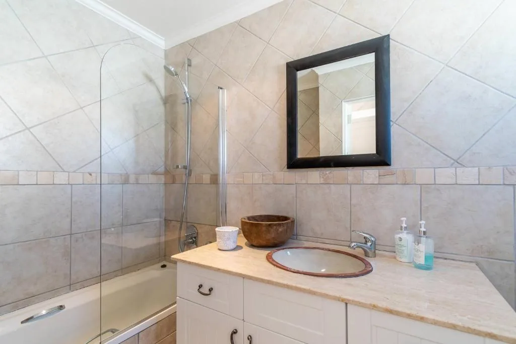Modern bathroom with glass shower enclosure, wooden vanity, and framed mirror