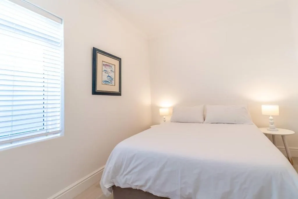 Bright bedroom with queen bed, white linens, and bedside lamps
